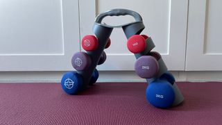 Three sets of color-coded neoprene dumbbells in a triangular rack