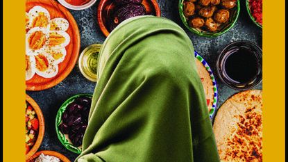 A woman wearing a headscarf looking at food as seen from behind.