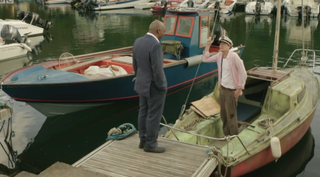 Humphrey and The Commissioner chat on Humphrey's rubbish boat in Death in Paradise
