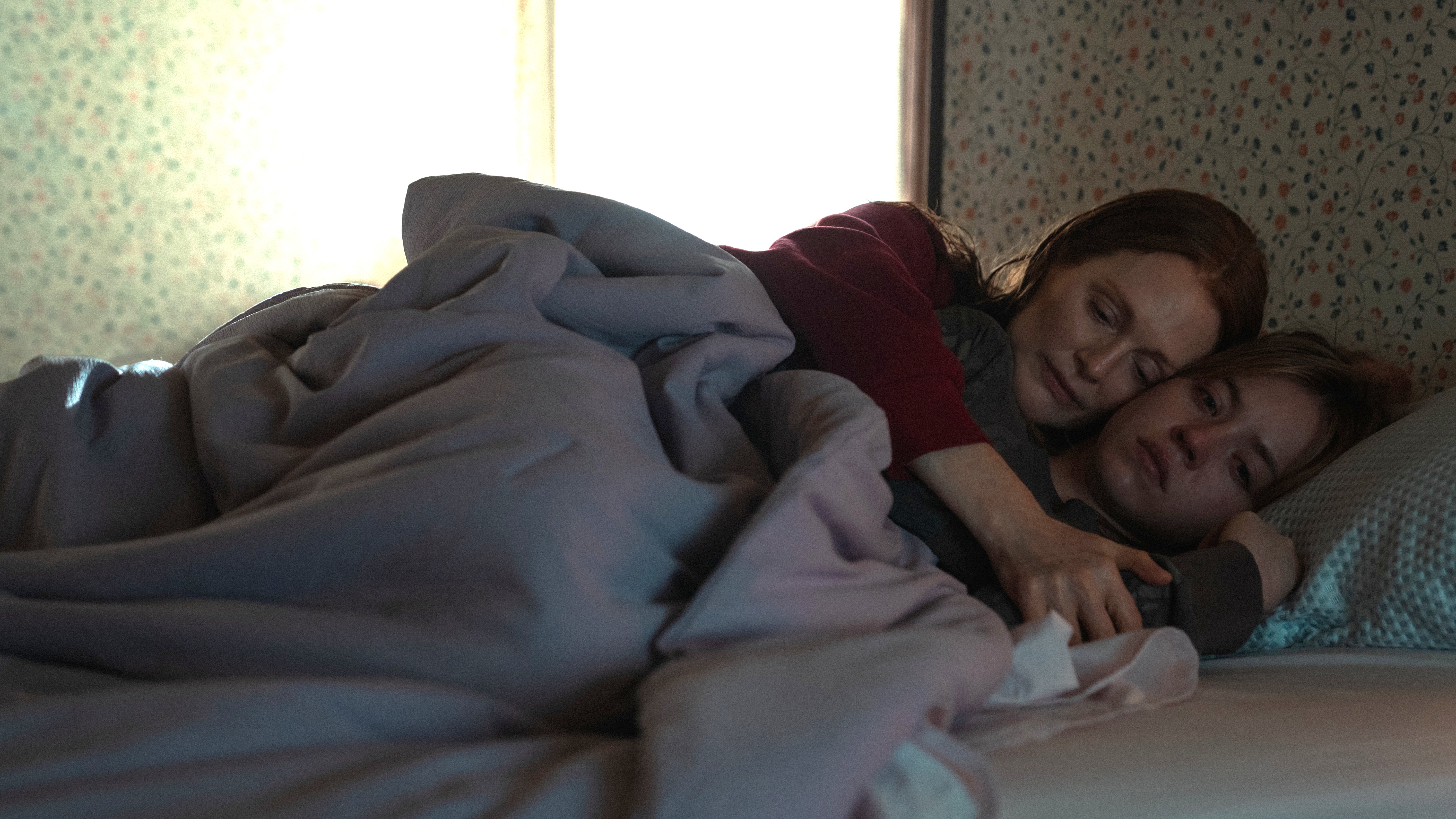 Kate (Julianne Moore) and Claire (Sydney Sweeney) lie in bed together in a scene from Apple TV Plus thriller "Echo Valley"