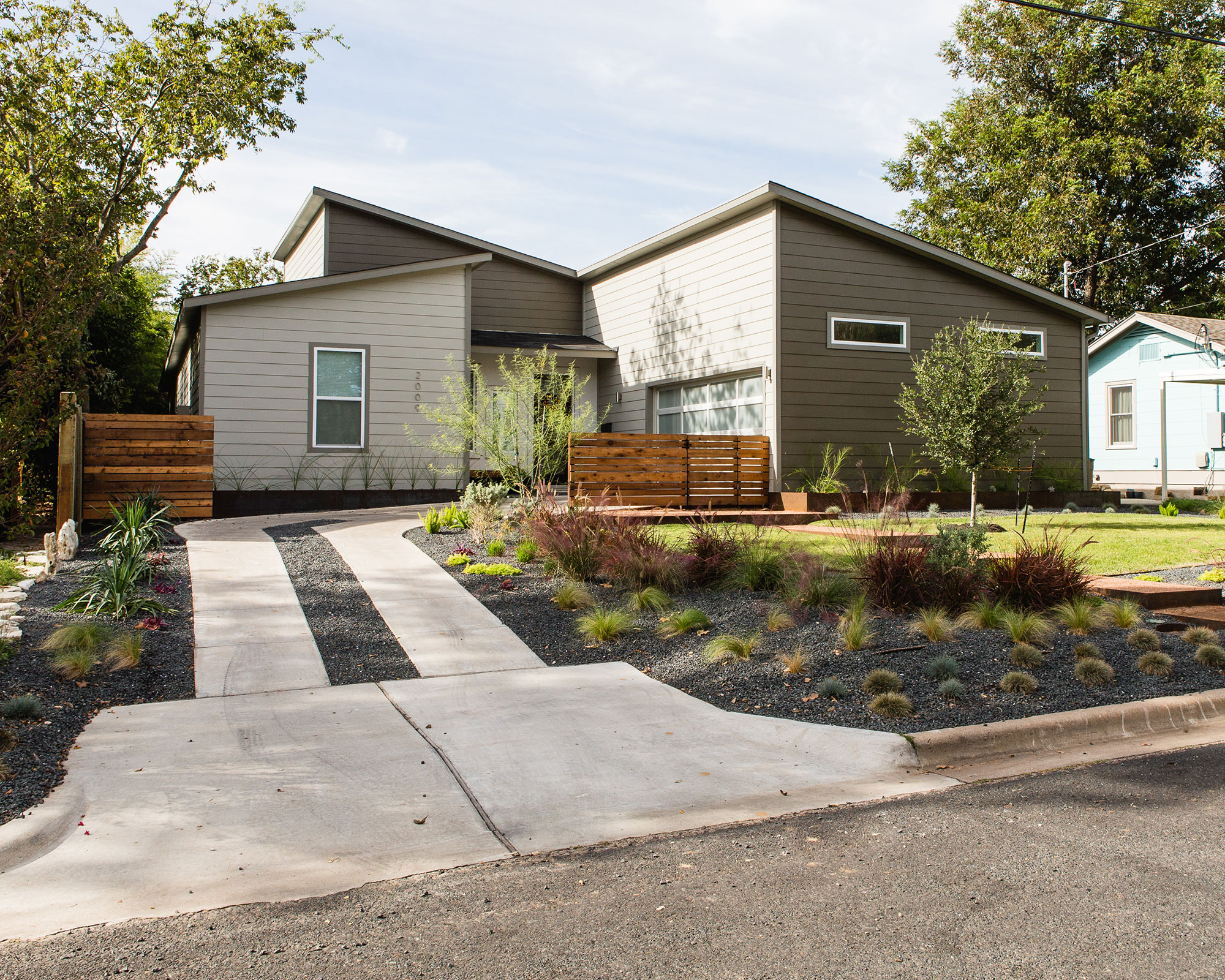 front yard with driveway, lawn and flowerbeds planted with grasses