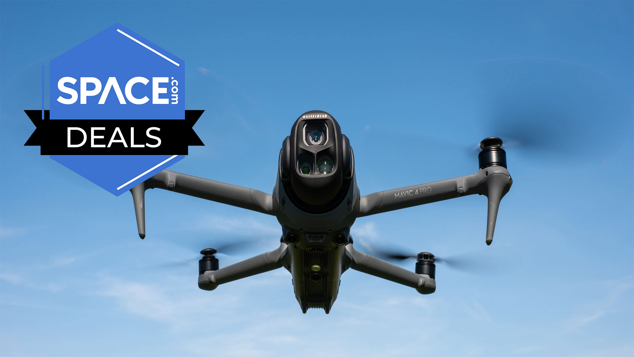 A black quadcopter is hovering in the air in front of clear blue skies with the Space.com logo in the top left corner. 