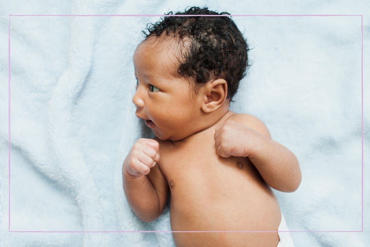 A newborn baby lying on a pale blue blanket