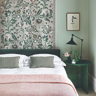 Bedroom with a bed, floral-print wallpaper and round bedside table