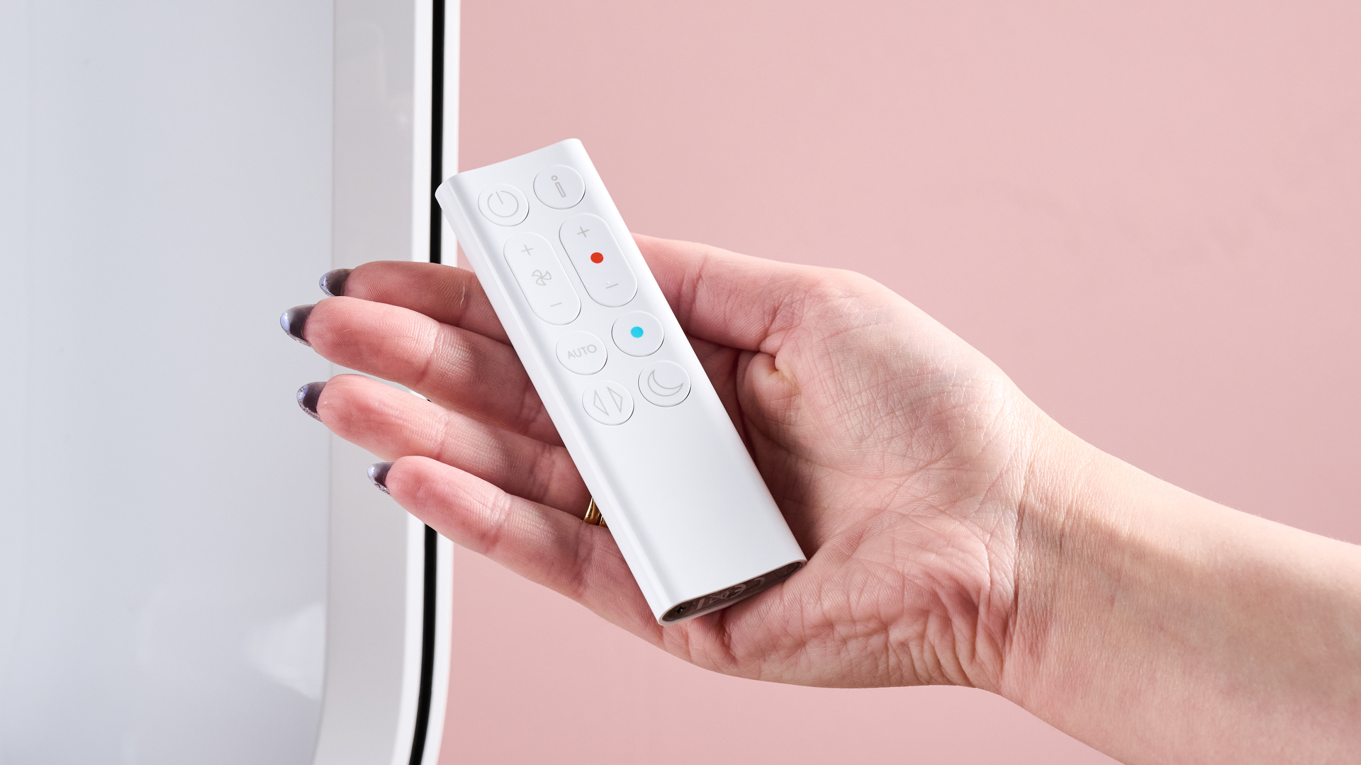 A woman is holding the remote control for the Dyson HP10 in the palm of her hand.