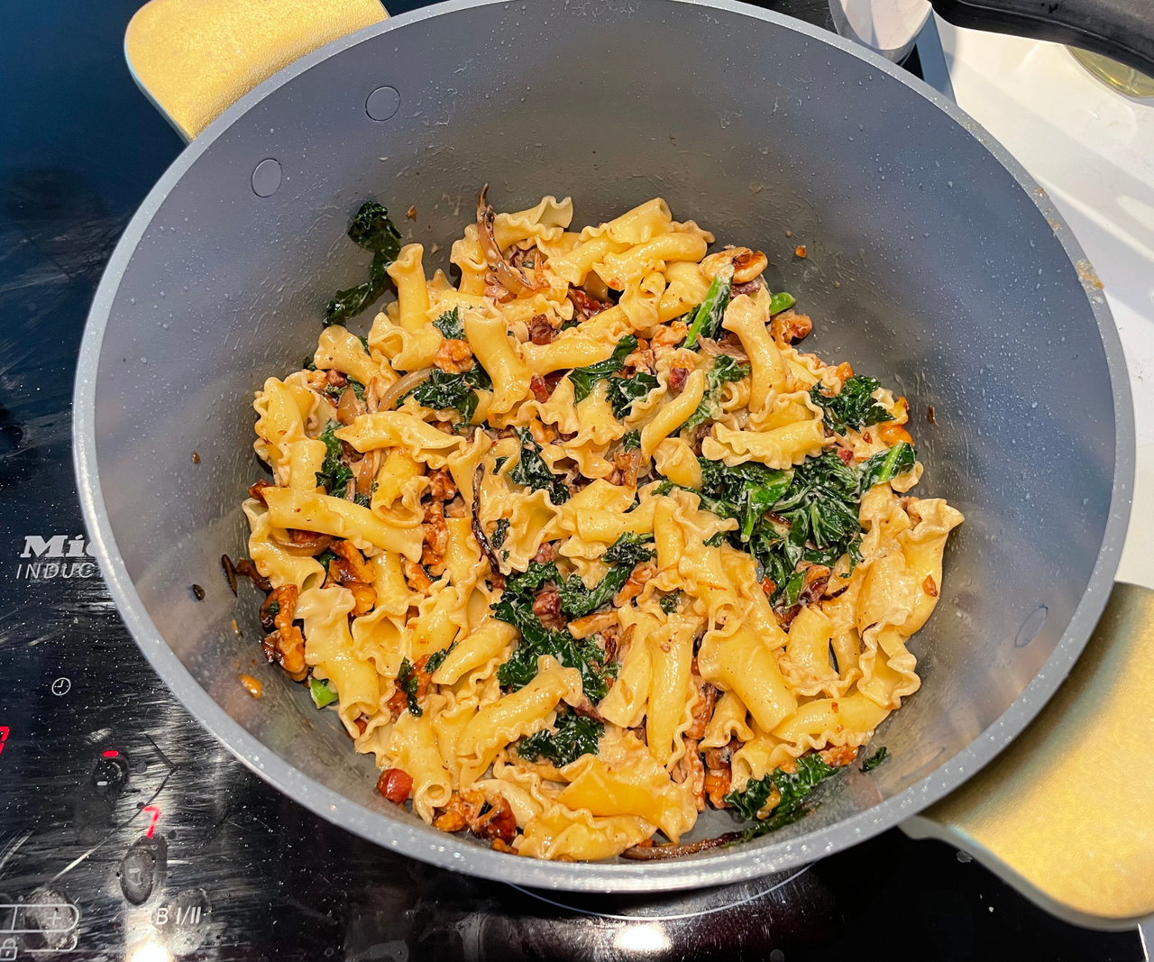A pasta dish in a blue ceramic Dutch oven on an electric stove.