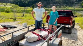 a man and teenage girl standing behind a whale skull strapped to a truck