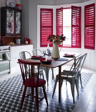Black and white kitchen with dining table in center and red shutters.