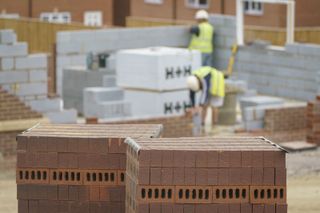 Bricks and blocks in a builders yard with builders in the background