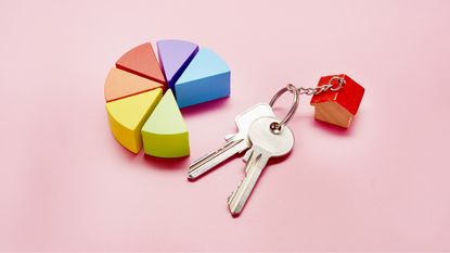 Plastic blocks in various colors form part of a pie chart while house keys sit next to it.