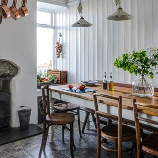 Country style dining room with white painted wall panelling and a wood topped farmhouse table
