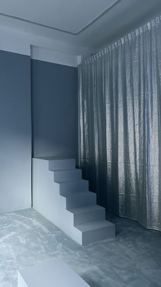 A blue room with staircase and silver curtain at Oxilia gallery