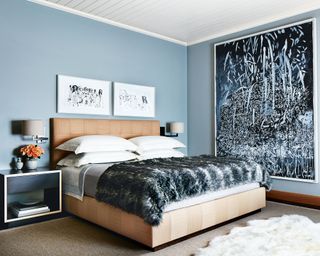 Bedroom with large-scale painting, pale blue walls and blush custom flannel bed with faux fur throw