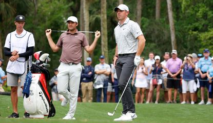 Rory McIlroy waits on the tee whilst Scheffler puts the club behind his head