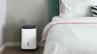 Meaco dehumidifier next to bed with white linen