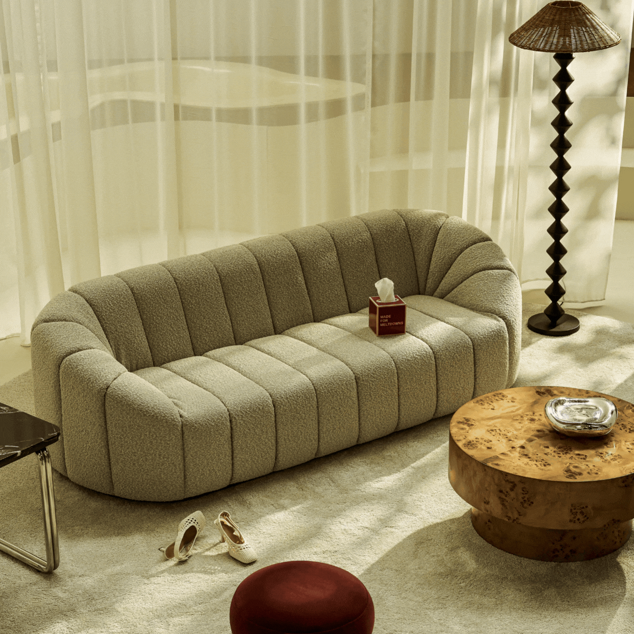 A rotating gif showcasing a chubby, oversized sofa in gray boucle fabric shown, respectively, in a sun-filled, beautifully decorated living room and a a product shot against a gray background.