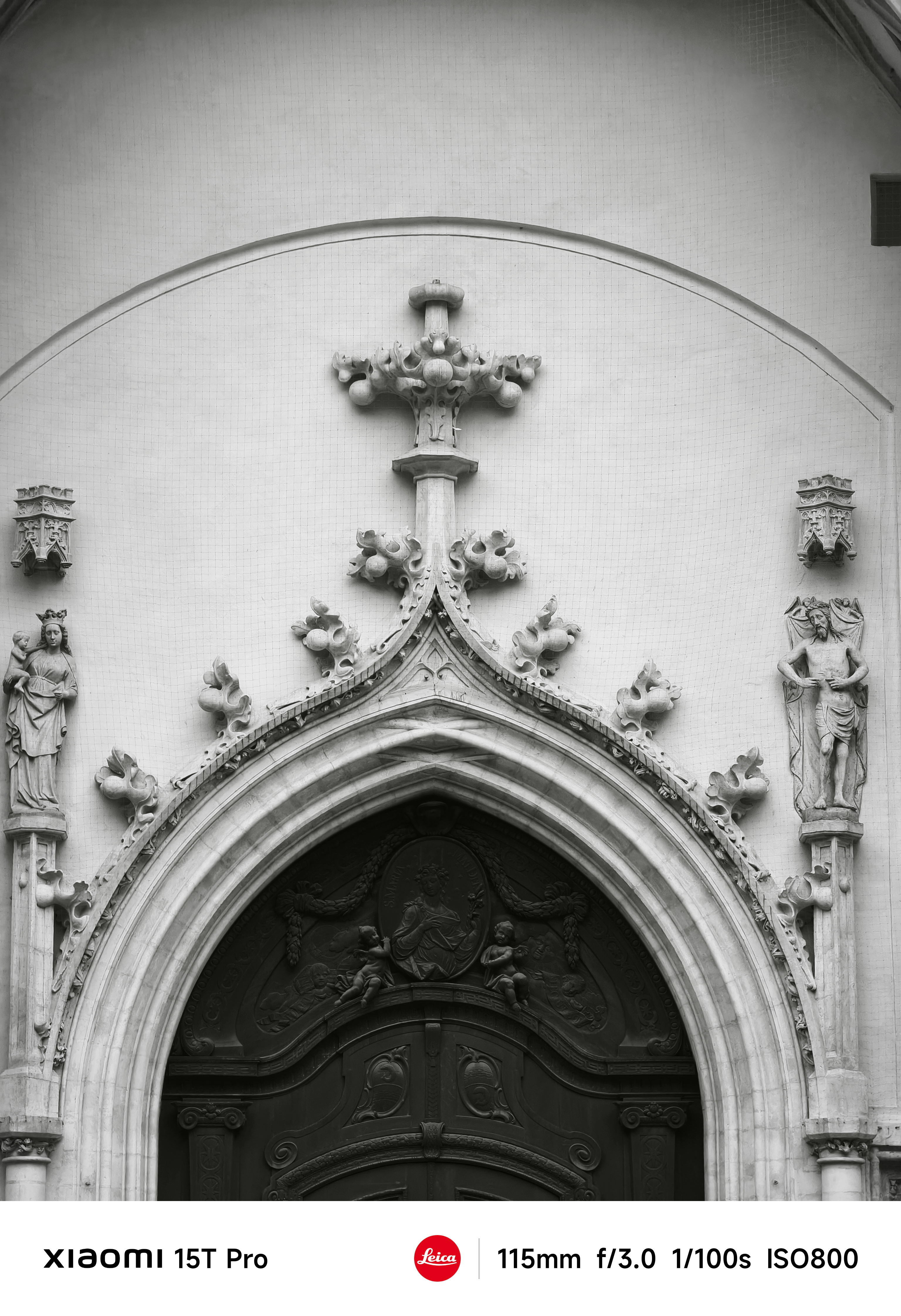 Top of a church entrance in Munich with decorative crosses and statues