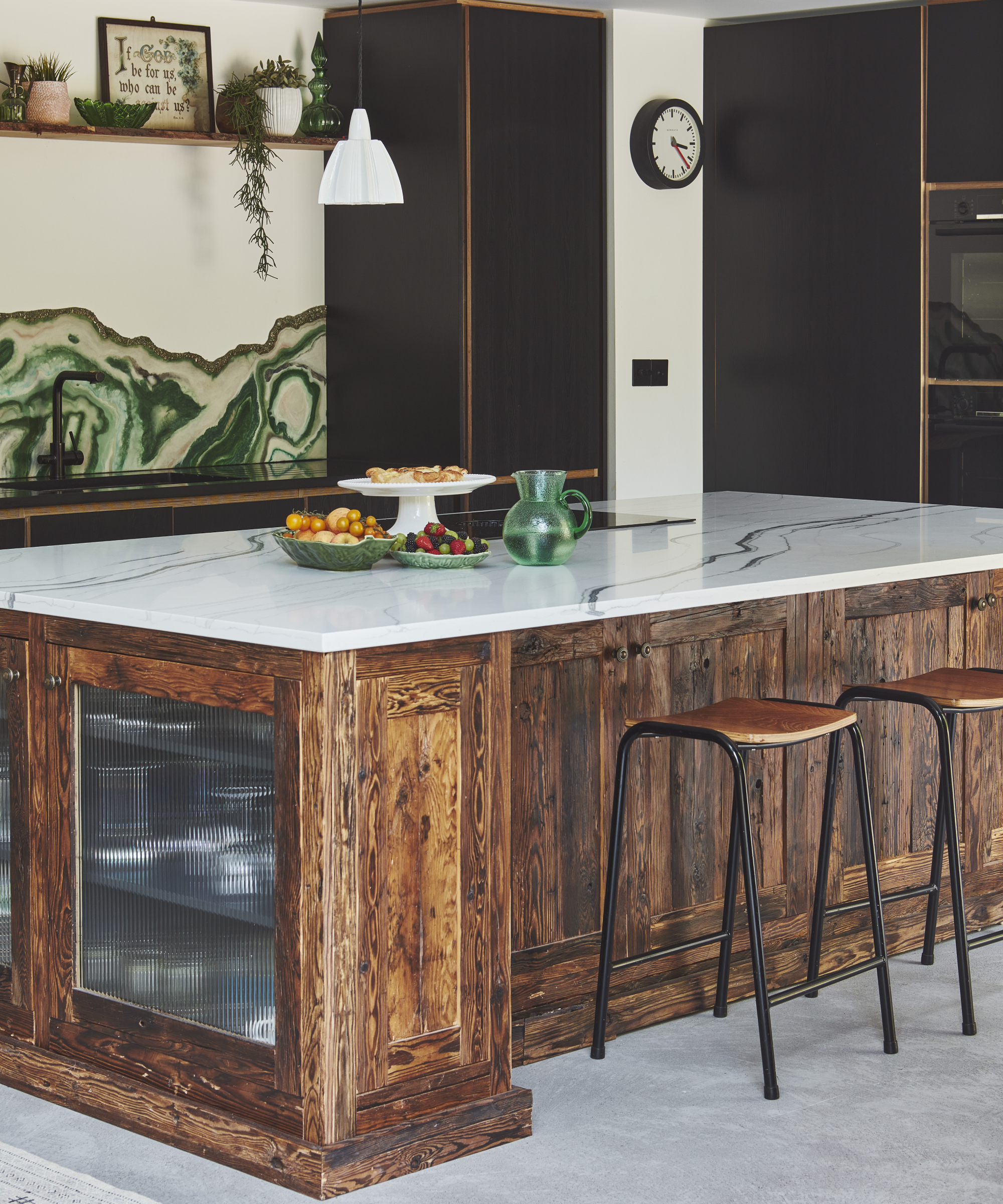 kitchen with aged wooden island, light marble top and bart stools, dark green splashback
