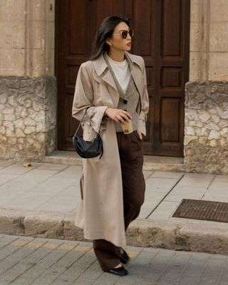 @michellelin.lin wears a trench coat, brown trousers and a beige cardigan