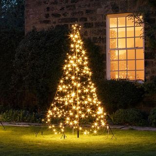 An LED lit Christmas tree outside suburban home with large framed window