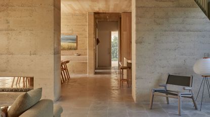 A minimalist home with a green chair, a standing rice paper lamp, and a path to an entryway
