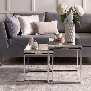 living room with mink grey wall and wooden floor with grey sofa and cushion with side table and flower vase