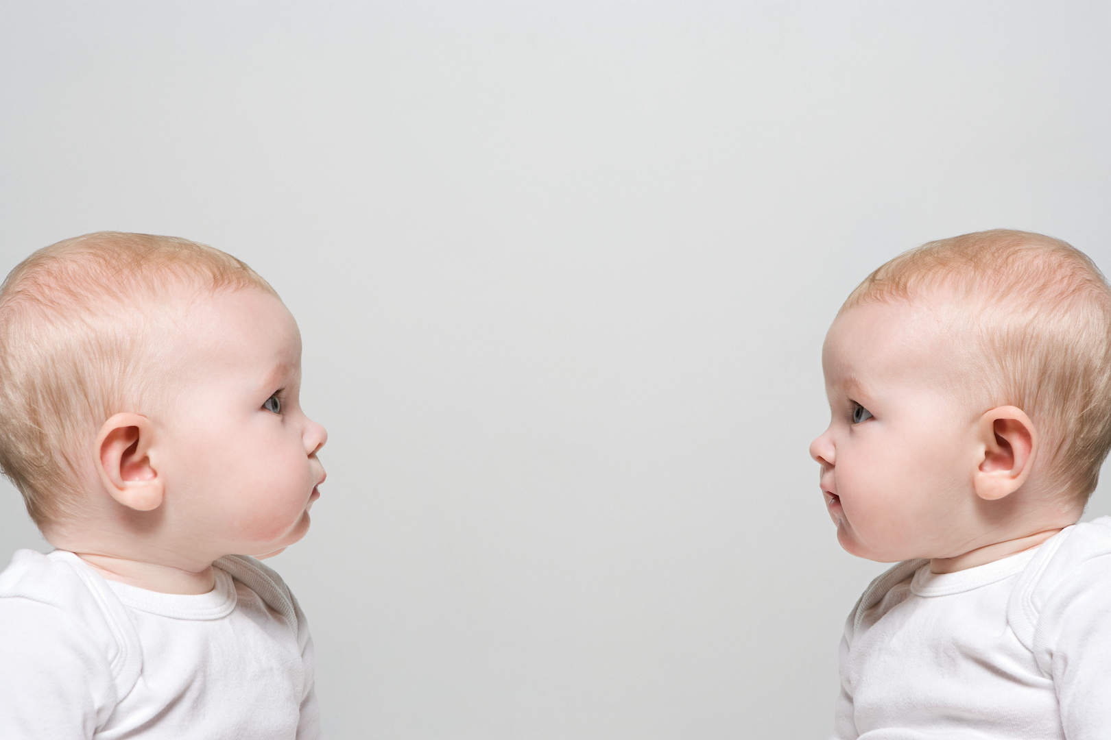 Profile view of two identical babies looking at one another.