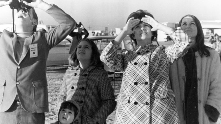 A black and white photo of a family looking up at the sky.