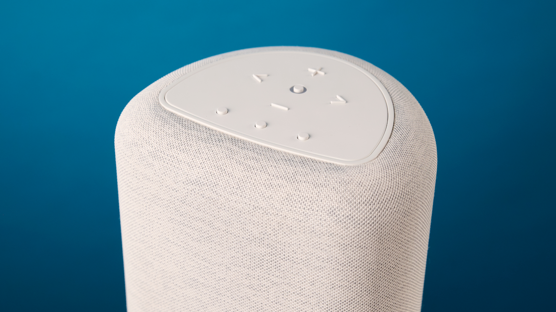 the bluesound pulse flex wi-fi speaker in pale gray photographed against the blue tom's guide background