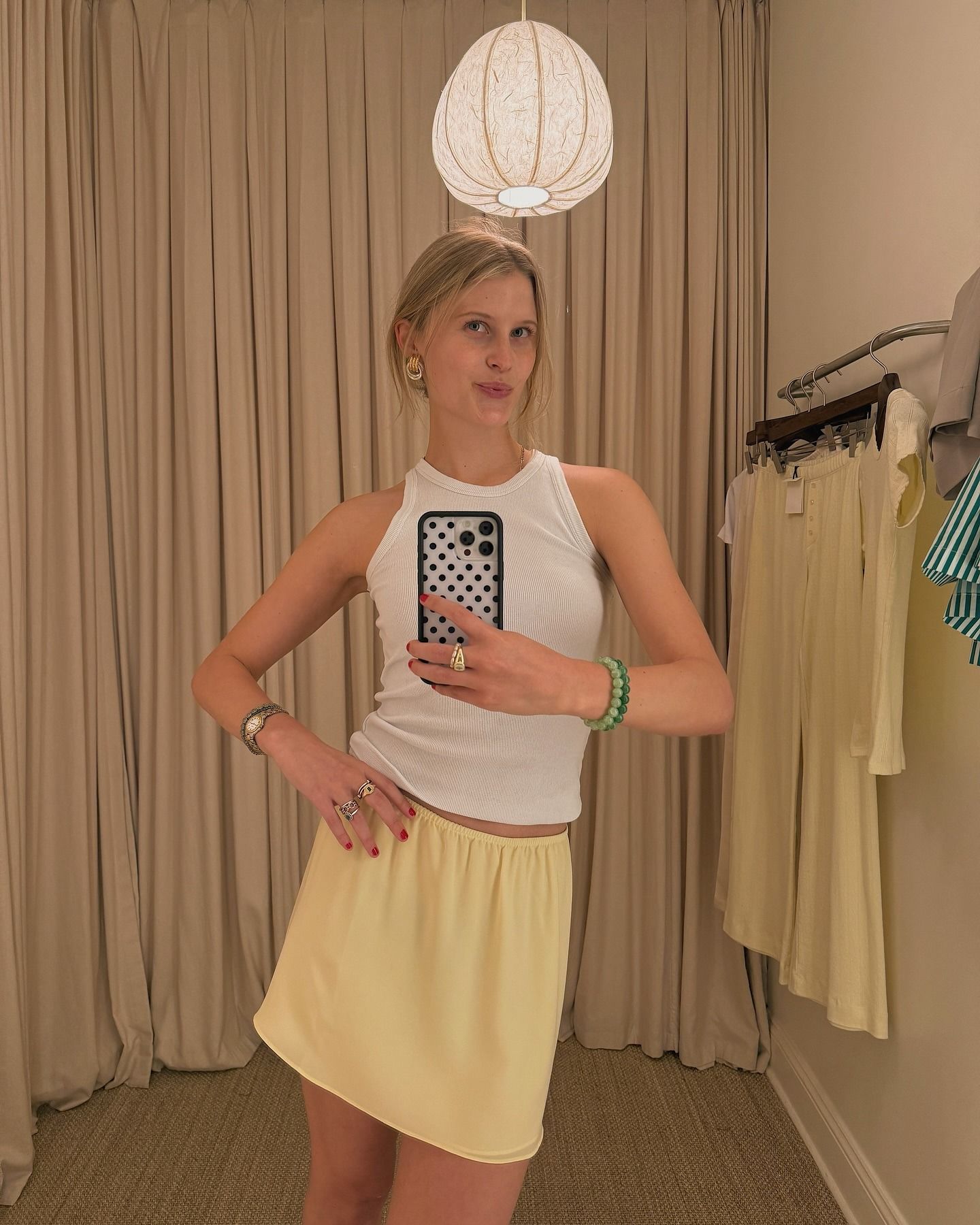 A woman wearing a yellow slip skirt and a white halter top.