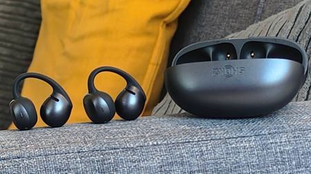 The Shokz OpenDots Air case and earbuds on the arm of a sofa.