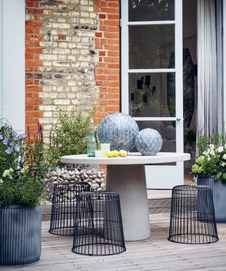 Large balcony garden ideas with round table and metal wire stools.