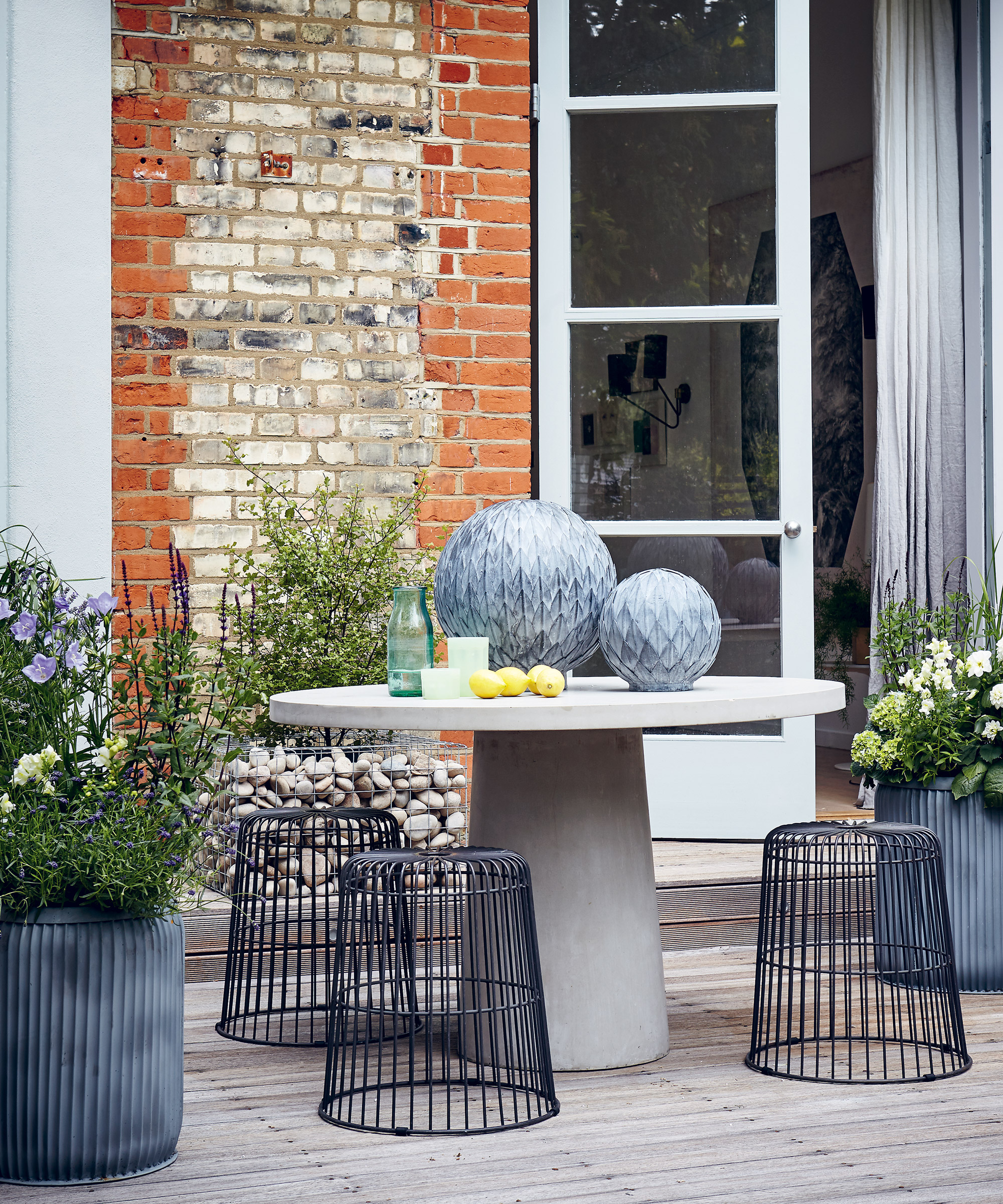 Large balcony garden ideas with round table and metal wire stools.