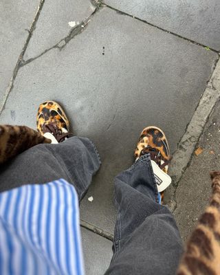 Influencer wearing Adidas Wales Bonner Leopard Print Ponyhair Samba with black jeans and blue-striped button-down shirt.