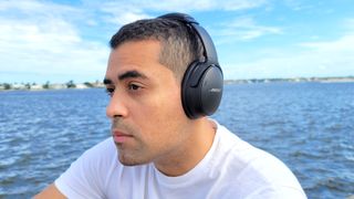 The reviewer wearing the Bose QuietComfort 45 headphones. In the background is the sea