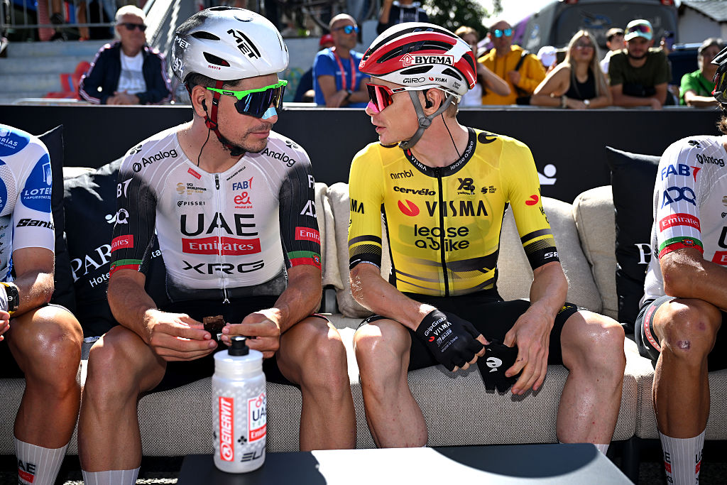 João Almeida and Jonas Vingegaard sit on a bench next to each other talking before stage 7 of the Vuelta a Espana