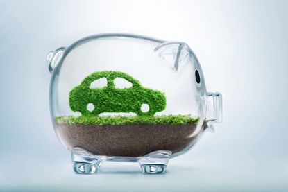 picture of a transparent piggy bank with an EV inside made of grass sitting on top of dirt