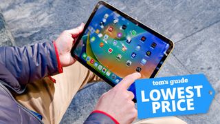 Apple iPad in hand with Tom's Guide Lowest Price badge