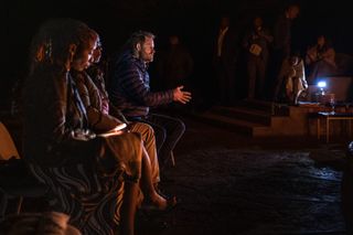 Prince Harry sitting around a campfire in Lesotho in the dark