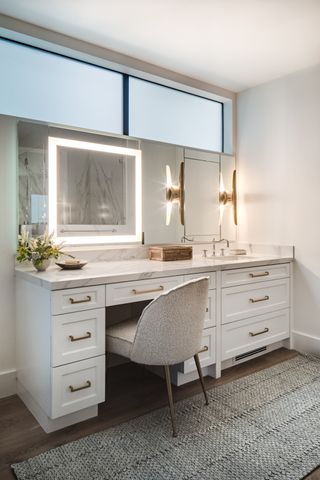 A bathroom vanity illuminated with strip lighting and a wall sconce
