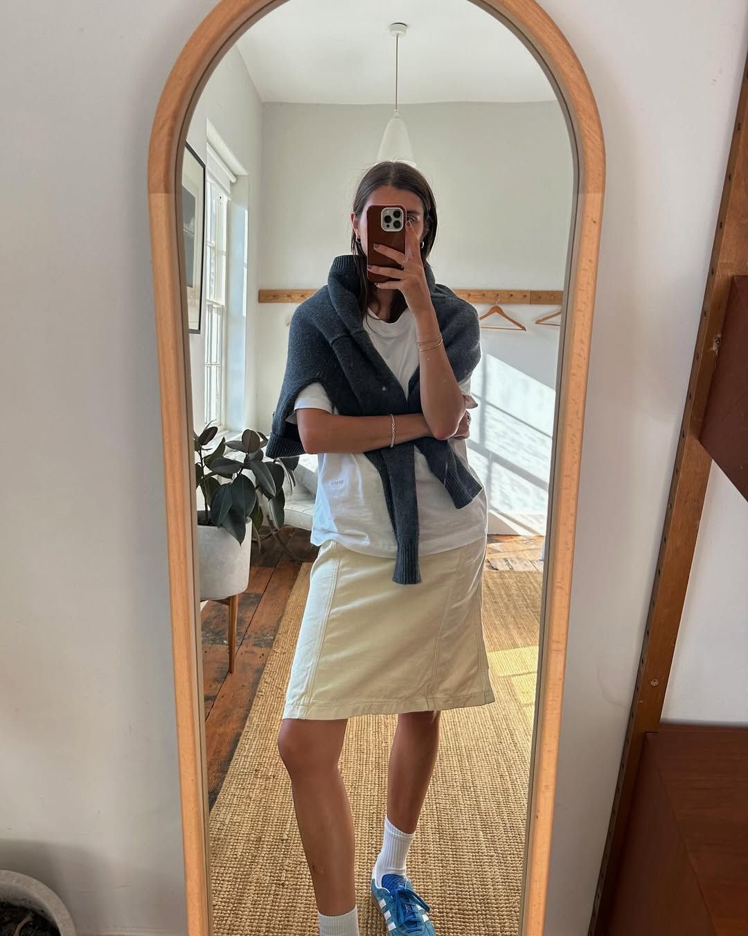 woman wearing midi skirt cardigan and adidas sneakers