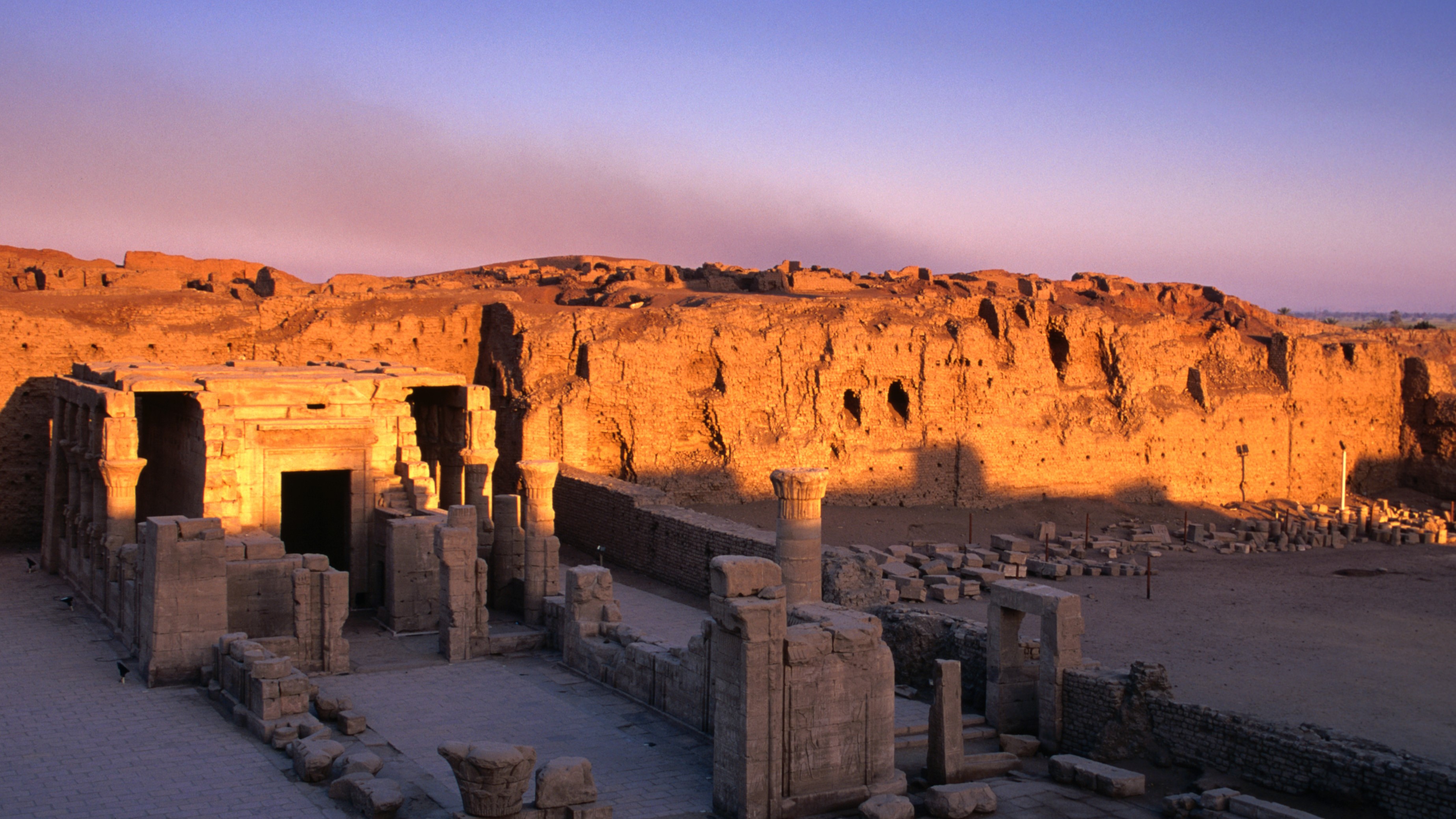 Sunrise starts to awaken the ruins of the small temple in front of the already lit grander remains of the Horus Temple.