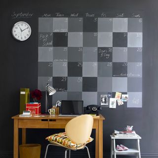 Home office with wall behind painted in chalkboard paint to create calendar