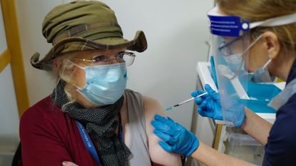 An NHS nurse vaccinates a patient