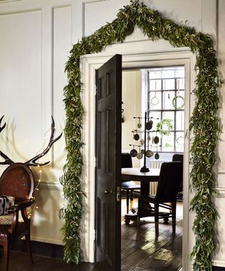 Eucalyptus garland around white door frame and black door and herb wreaths hanging in front of window