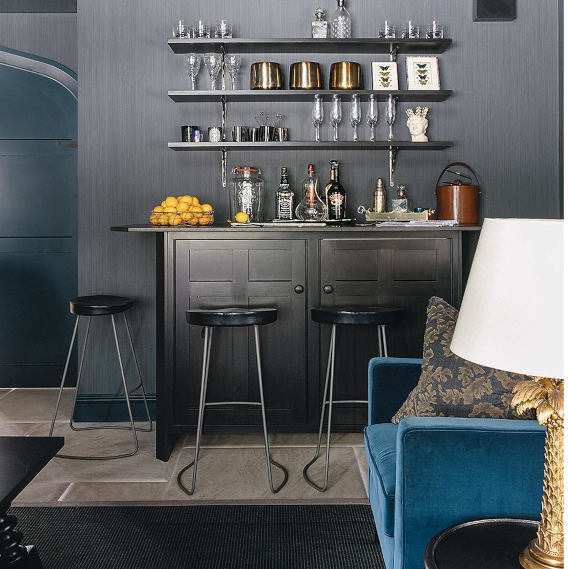 silver shelves with silver cabinets, black stools and a blue sofa