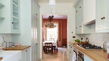 A kitchen with mint-toned cabinets and wooden countertop