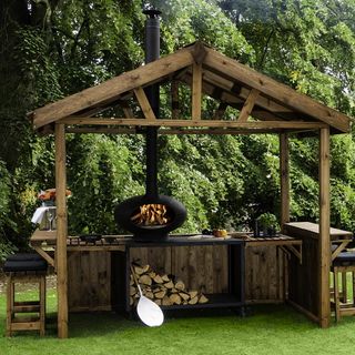 outdoor cooking with hut and chimney and wood stacks