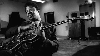 Black and white photo of BB King sat down holding his Gibson guitar