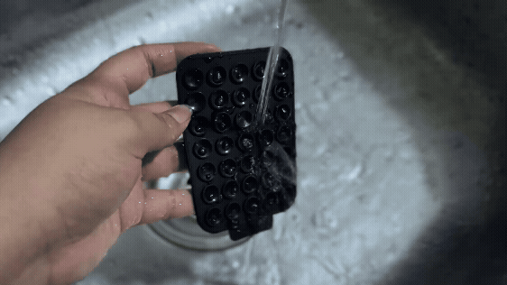 Washing the BURGA StickPad in running water in a sink.